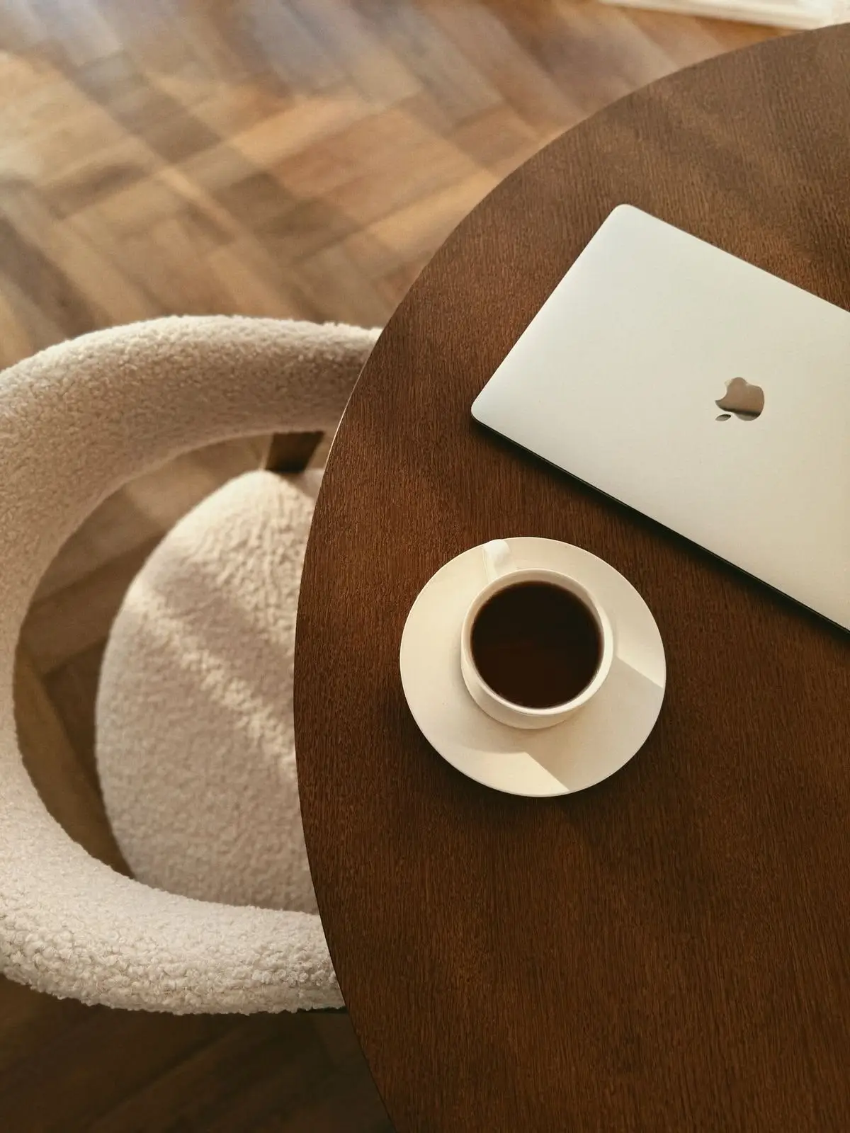 Laptop and coffee on a table, representing the quiet planning work behind pricing a therapist website