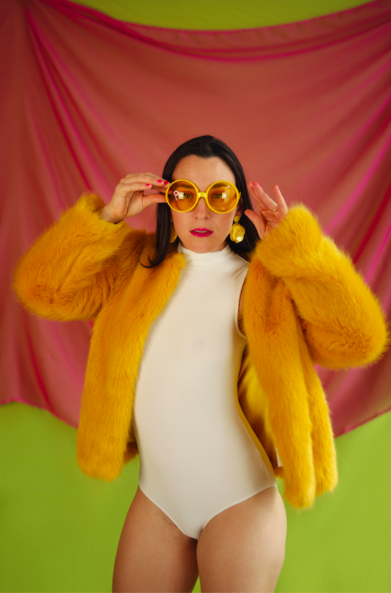 Mary in a yellow fur coat and round sunglasses